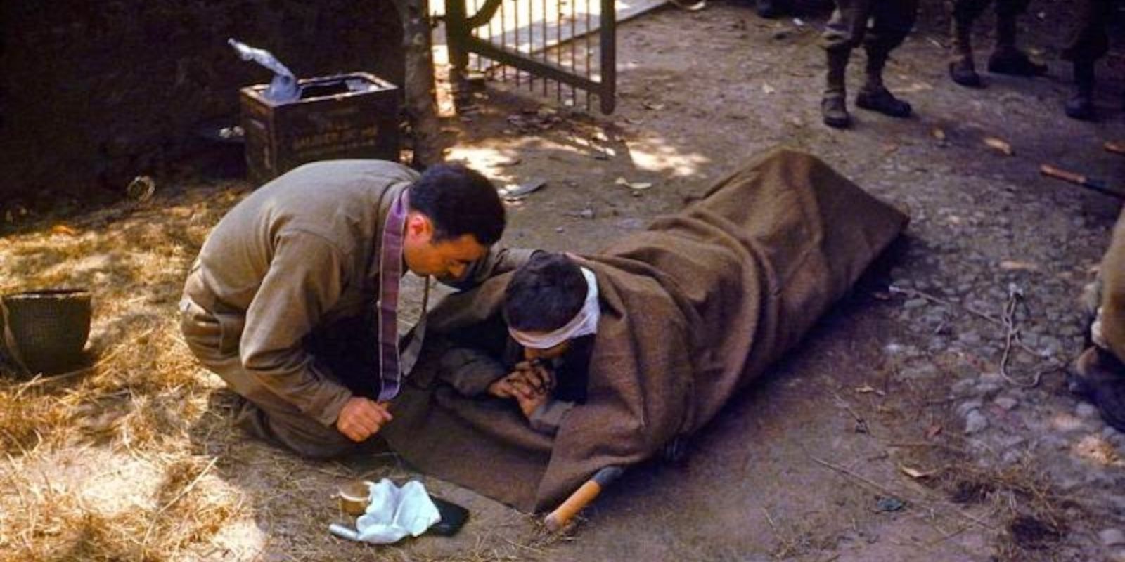 Um capelão do Exército dos EUA oferece conforto e os últimos ritos a um soldado ferido no campo de batalha na França. A fotografia é um testemunho solene da fé e da compaixão em meio à brutalidade do combate. Autor: Frank Scherschel / LIFE Picture Collection.