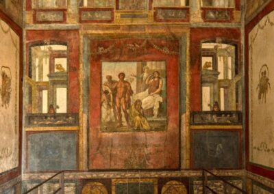 Vista geral do interior da Casa dos Vettii mostrando a arquitetura romana preservada. Os afrescos cobrem todas as paredes com painéis mitológicos emoldurados. A erupção do Vesúvio em 79 d.C. selou a casa sob cinzas, preservando-a por quase 2 mil anos.