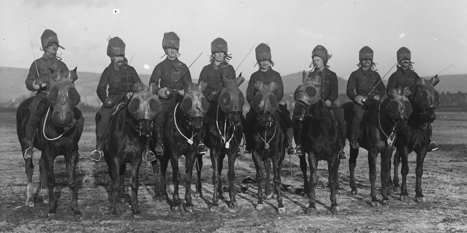 Cavaleiros britânicos montados com seus cavalos equipados com máscaras de gás durante a Primeira Guerra Mundial. A imagem mostra a tentativa de proteger os animais contra ataques de gás venenoso, uma das armas mais terríveis do conflito.