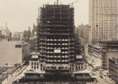 Uma vista aérea da construção do Rockefeller Center em seus estágios iniciais, mostrando a grandiosidade do projeto que transformaria o horizonte de Nova York. Esta imagem destaca o esforço monumental e a escala da obra durante a década de 1930. Fonte: Rockefeller Center.