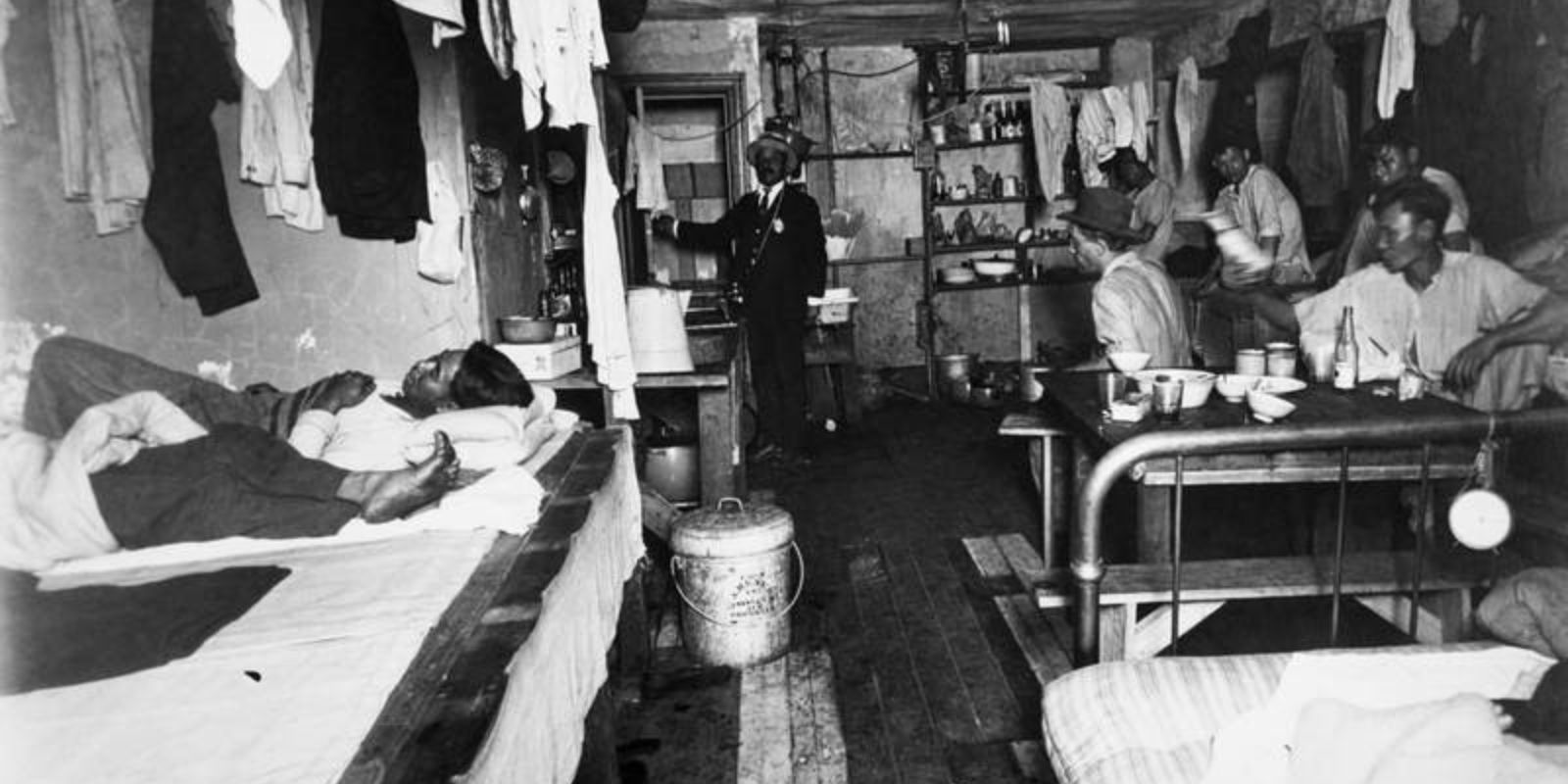 Crianças dormem amontoadas em um cortiço insalubre em Nova York, uma cena documentada por Jacob Riis no final do século XIX. A fotografia expõe as duras condições de vida enfrentadas por muitos imigrantes e pobres, revelando a face oculta da prosperidade americana. Fonte: Jacob A. Riis / Museum of the City of New York.