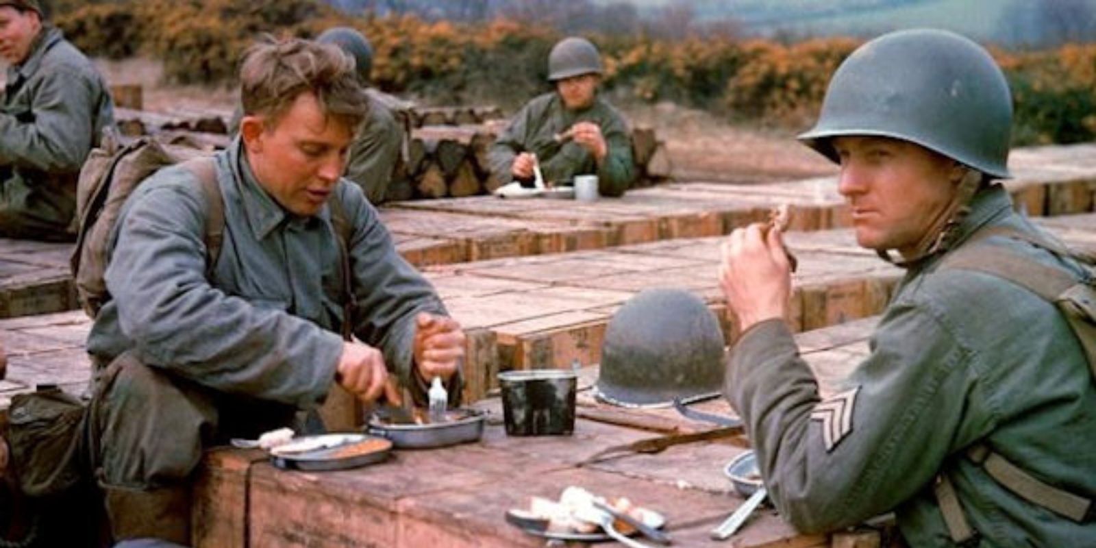 Em um momento de pausa durante os preparativos para a invasão, engenheiros de combate americanos compartilham uma refeição, usando caixas de munição como mesa improvisada. A cena captura a surreal justaposição da rotina diária com a iminência da guerra. Frank Scherschel / LIFE Picture Collection.