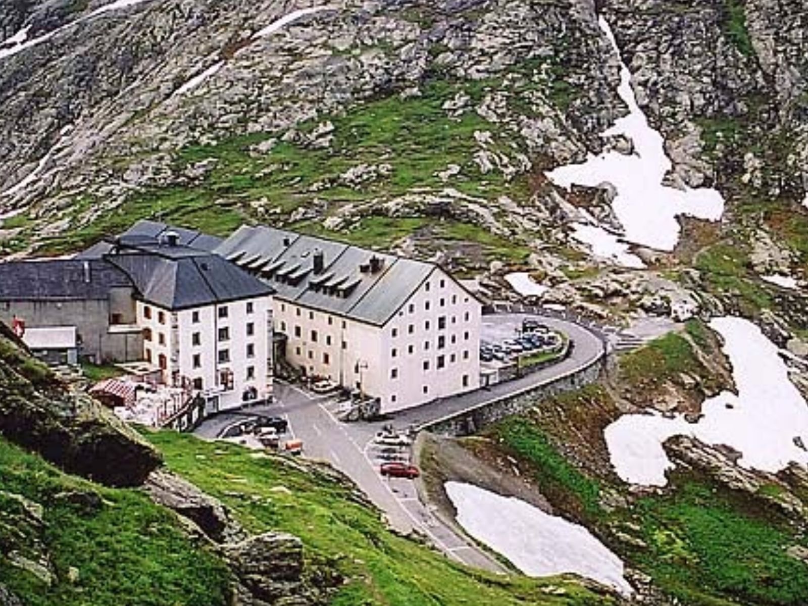 O Hospício de Gran St Bernard, fundado no século XI por São Bernardo de Menthon, está localizado em uma passagem montanhosa dos Alpes, a 2.473 metros acima do nível do mar, na fronteira entre a Suíça e a Itália. Este hospício servia como abrigo para peregrinos e viajantes que cruzavam os Alpes, oferecendo-lhes refúgio seguro contra as condições climáticas extremas.