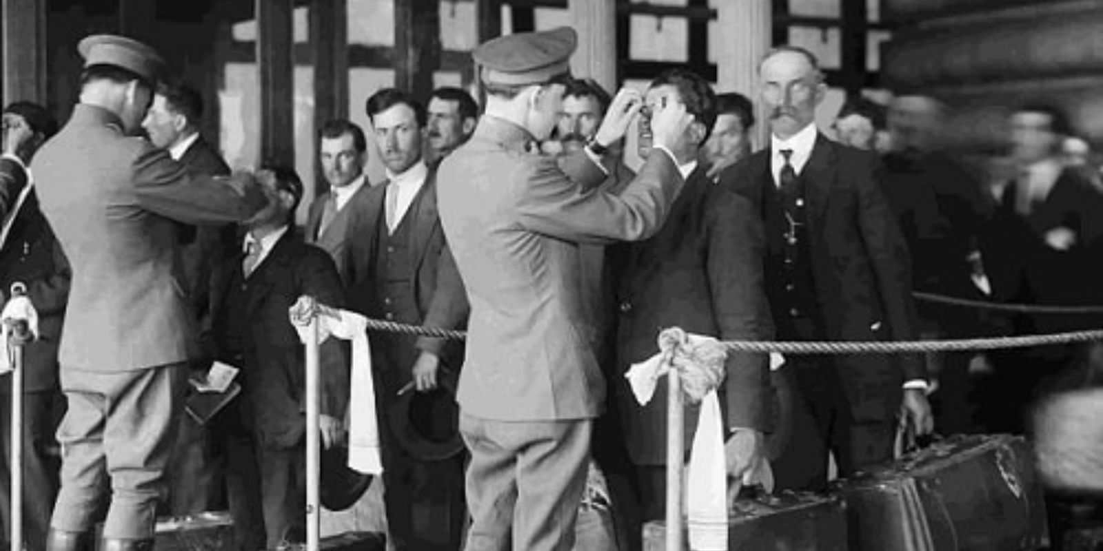 Imigrantes passam por uma rigorosa inspeção de saúde em Ellis Island, Nova York, um processo crucial para a entrada nos Estados Unidos. A imagem ilustra os desafios burocráticos e sanitários enfrentados por aqueles que buscavam uma nova oportunidade no país. Fonte: Biblioteca do Congresso dos EUA.