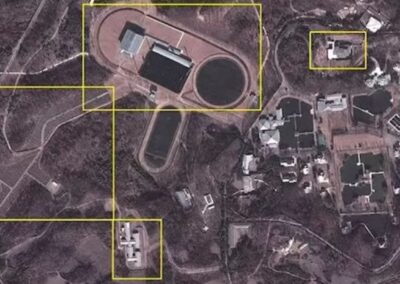 Imagem de satélite de alta resolução capturada em 2012 revela detalhes do complexo Kang Dong. Visível estão o edifício principal ao redor de um lago com fonte ornamental, múltiplas residências para membros da família Kim, instalações esportivas incluindo campo de futebol e hipódromo, além das duas linhas de segurança que cercam todo o perímetro de 4 quilômetros quadrados. Fonte: North Korea Economy Watch / Google Earth