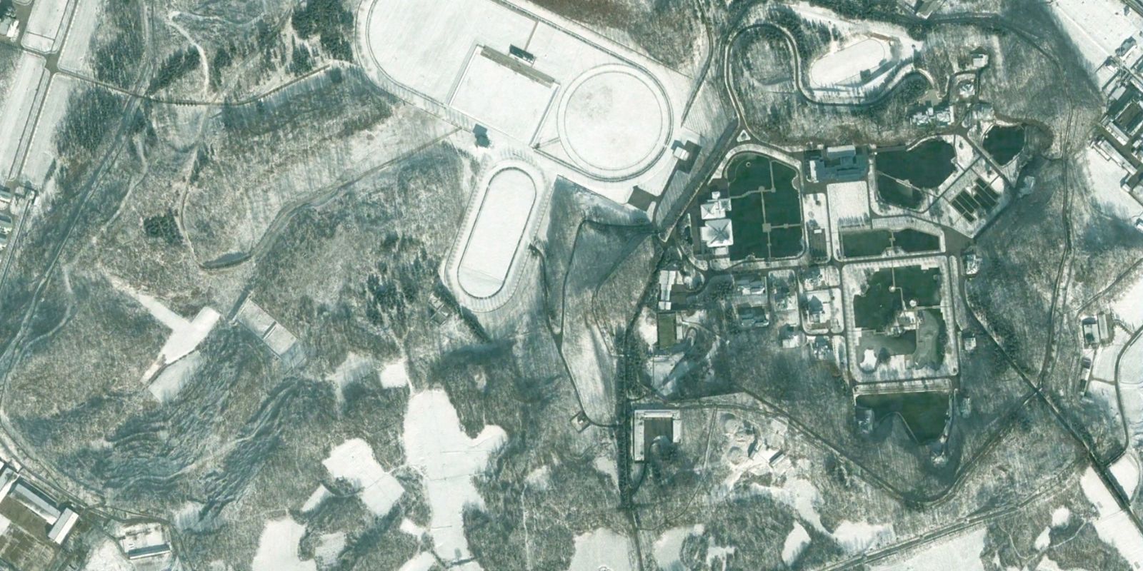 Imagem de satélite mostra a estação ferroviária exclusiva construída após 2006 para servir o complexo Kang Dong. Apenas trens especiais transportando a família Kim e convidados VIP podem parar nesta estação. A infraestrutura conecta o palácio secreto diretamente à rede ferroviária nacional, permitindo viagens discretas sem passar por estações públicas onde cidadãos comuns poderiam ver os líderes. Fonte: North Korea Economy Watch / Google Earth