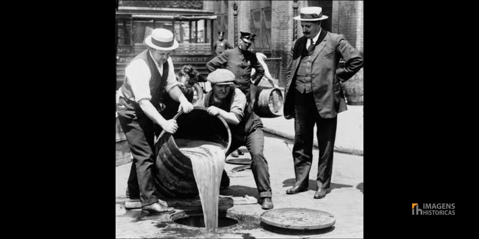 Agentes da polícia de Nova York, sob a supervisão do Comissário John A. Leach, derramam bebidas alcoólicas em um bueiro após uma batida durante o auge da Lei Seca. Esta cena ilustra os esforços das autoridades para fazer cumprir a proibição. Fonte: Library of Congress Prints and Photographs Division Washington, D.C.