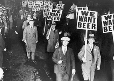 Manifestantes protestam contra a Lei Seca nos Estados Unidos, exibindo cartazes com a frase "We Want Beer" (Queremos Cerveja). A imagem reflete a insatisfação popular com a proibição do álcool e a resistência à legislação. Fonte: Library of Congress Prints and Photographs Division Washington, D.C.