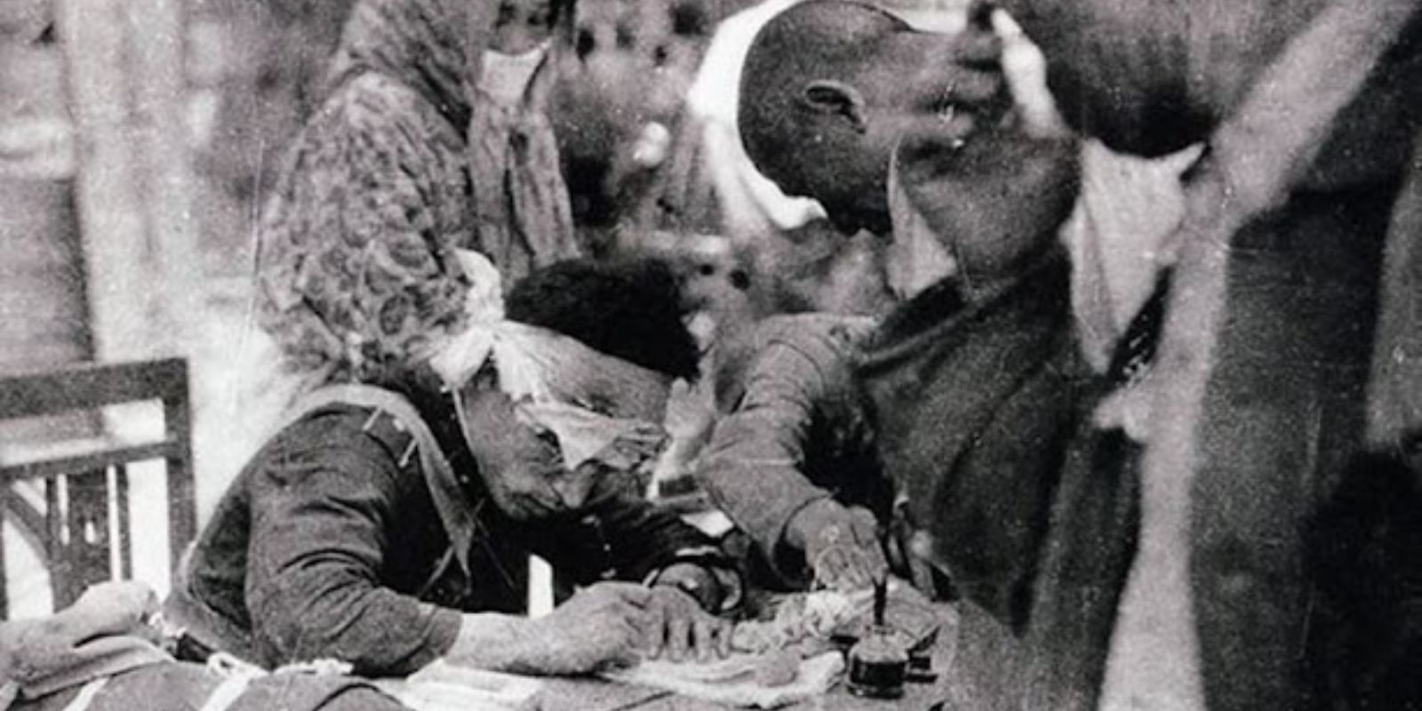 Terceira fotografia de Matsushige, tirada mais tarde no mesmo dia. Um policial com a cabeça enfaixada emite certificados para civis. Mesmo ferido, continuava cumprindo seu dever em meio ao caos. A cena mostra a tentativa de manter alguma ordem após a devastação. Fonte: Max McCoy / Zero Minutes to Midnight