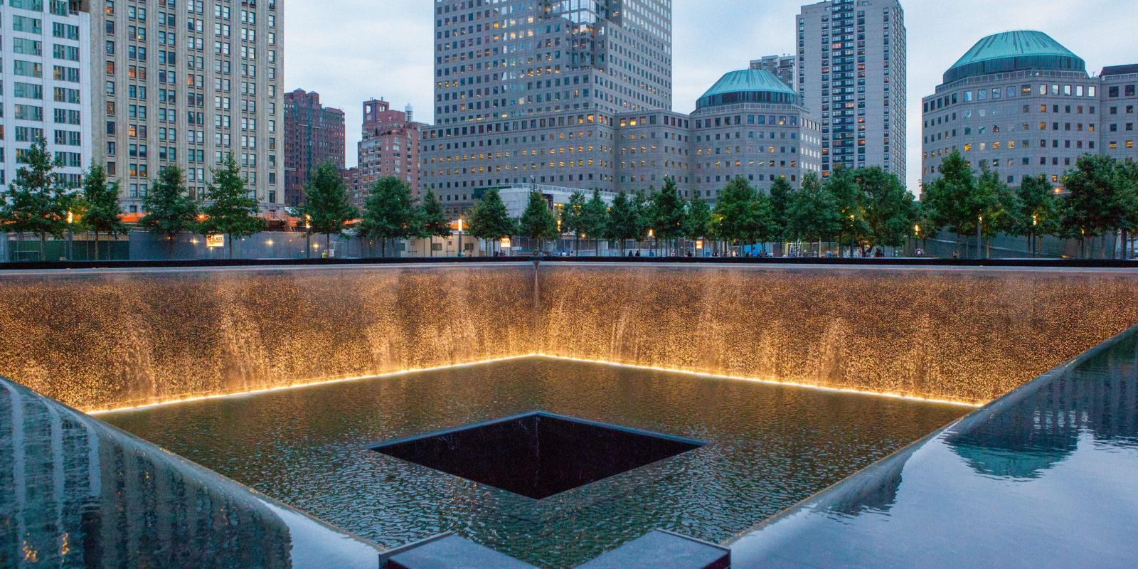Memorial Nacional do 11 de Setembro em Nova York, localizado no Ground Zero onde ficavam as Torres Gêmeas. O memorial possui duas piscinas refletoras no lugar exato das torres, com os nomes de todas as 2.977 vítimas gravados em bronze. O nome de Mychal Judge está inscrito junto com todos os outros que perderam suas vidas naquele dia. Fonte: ILoveNY.com / New York State Tourism