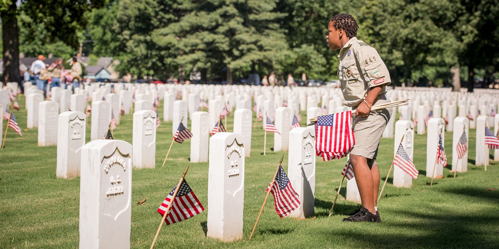 Cemitério nacional americano decorado com bandeiras no Memorial Day. A tradição de colocar bandeiras em cada túmulo de veterano começou após a Guerra Civil e continua até hoje. O Cemitério Fort Logan em Denver, onde Dorris Fielder foi fotografada em 1983, recebe milhares de visitantes todo Memorial Day para honrar os que serviram. Fonte: Aaron on Scouting / Boy Scouts of America.