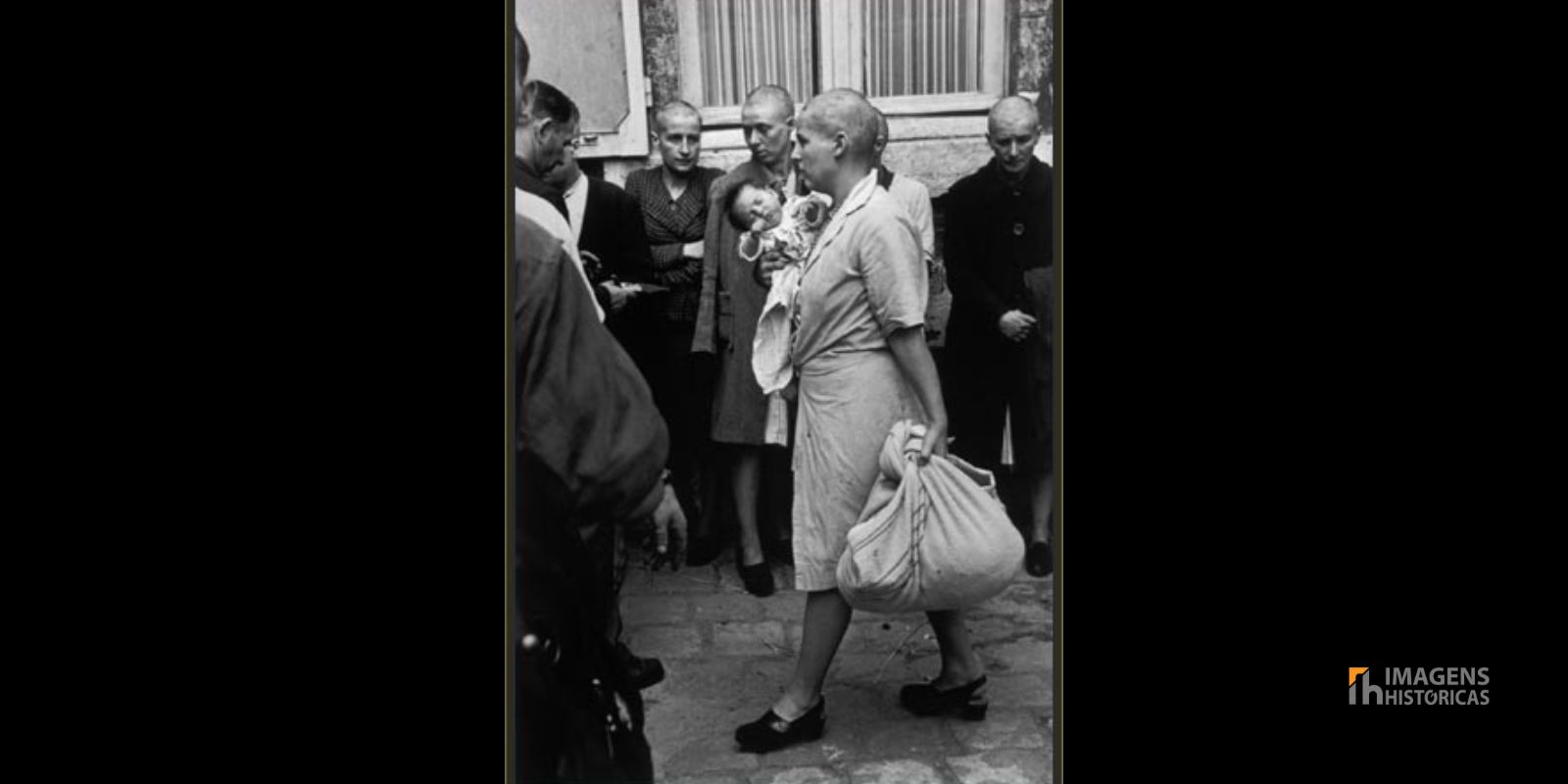 Uma mulher de cabeça raspada caminha pelas ruas carregando seu bebê, fruto de um relacionamento com um soldado alemão. A imagem captura a solidão e a vulnerabilidade das vítimas da "justiça popular". Fonte: Robert Capa / Magnum Photos.
