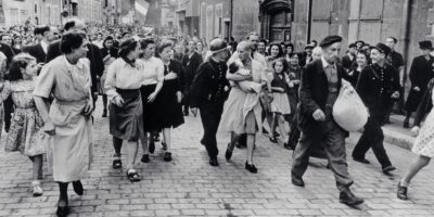 A icônica fotografia de Robert Capa mostra uma mulher francesa, acusada de "colaboração horizontal", sendo escoltada por uma multidão enfurecida em Chartres, em 18 de agosto de 1944. Carregando seu bebê, fruto de um relacionamento com um soldado alemão, ela se tornou o símbolo da punição brutal infligida a milhares de mulheres após a libertação. Fonte: Robert Capa / Magnum Photos.