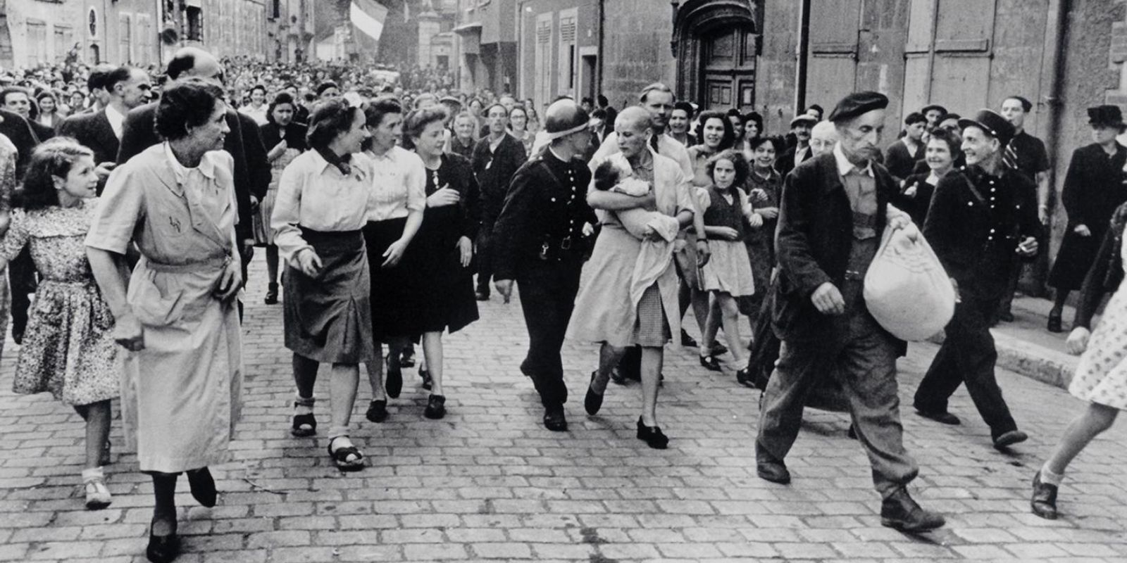 A icônica fotografia de Robert Capa mostra uma mulher francesa, acusada de "colaboração horizontal", sendo escoltada por uma multidão enfurecida em Chartres, em 18 de agosto de 1944. Carregando seu bebê, fruto de um relacionamento com um soldado alemão, ela se tornou o símbolo da punição brutal infligida a milhares de mulheres após a libertação. Fonte: Robert Capa / Magnum Photos.