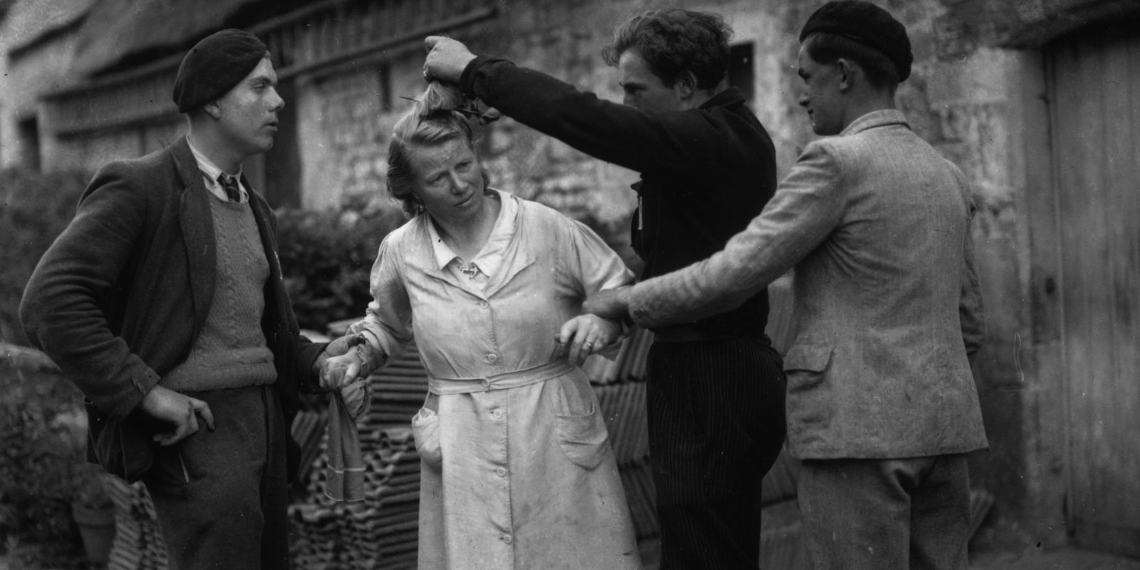 Uma mulher francesa é publicamente humilhada enquanto tem sua cabeça raspada por membros da Resistência Francesa em 1944. A cena, que se repetiu por toda a França, era um ritual de punição e purificação simbólica. Fonte: PBS / Getty Image.