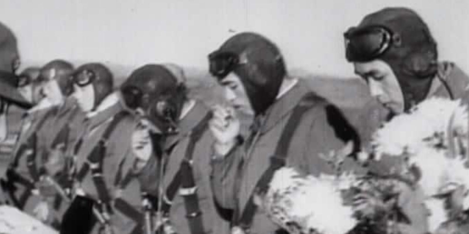 Jovens pilotos kamikazes do 72º Esquadrão Shinbu recebem flores de estudantes antes de partirem para uma missão em Okinawa, em 26 de maio de 1945. A imagem captura a mistura de cerimônia e resignação que cercava esses sacrifícios. Jovens pilotos kamikazes do 72º Esquadrão Shinbu recebem flores de estudantes antes de partirem para uma missão em Okinawa, em 26 de maio de 1945. A imagem captura a mistura de cerimônia e resignação que cercava esses sacrifícios.