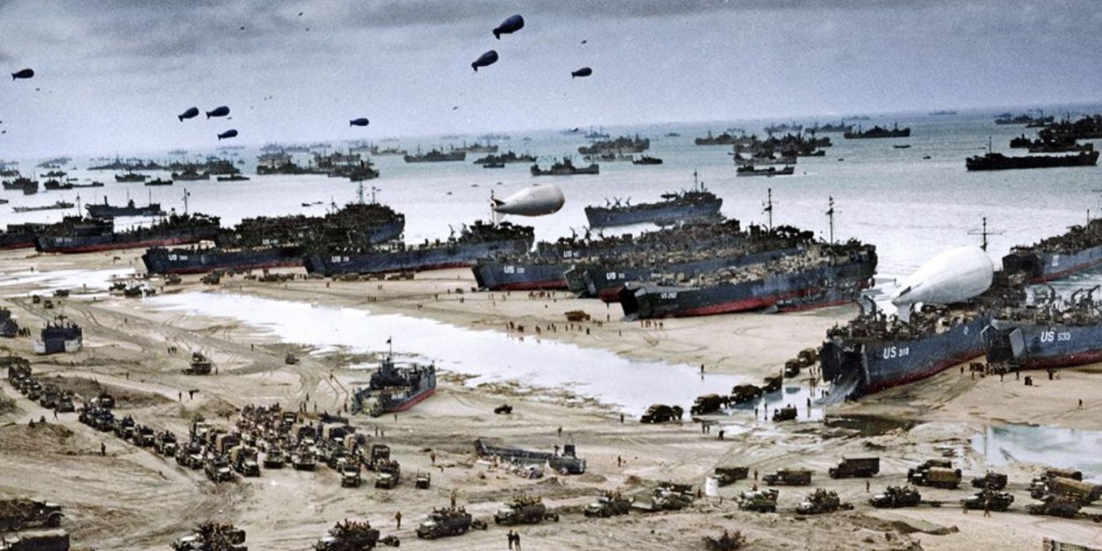 Uma vista aérea colorida mostra a imensa logística na praia da Normandia dias após o desembarque inicial. Navios, veículos e suprimentos se acumulam na costa, enquanto paraquedistas ainda descem ao fundo, ilustrando a contínua consolidação da cabeça de ponte aliada. Fonte: Marina Amaral.