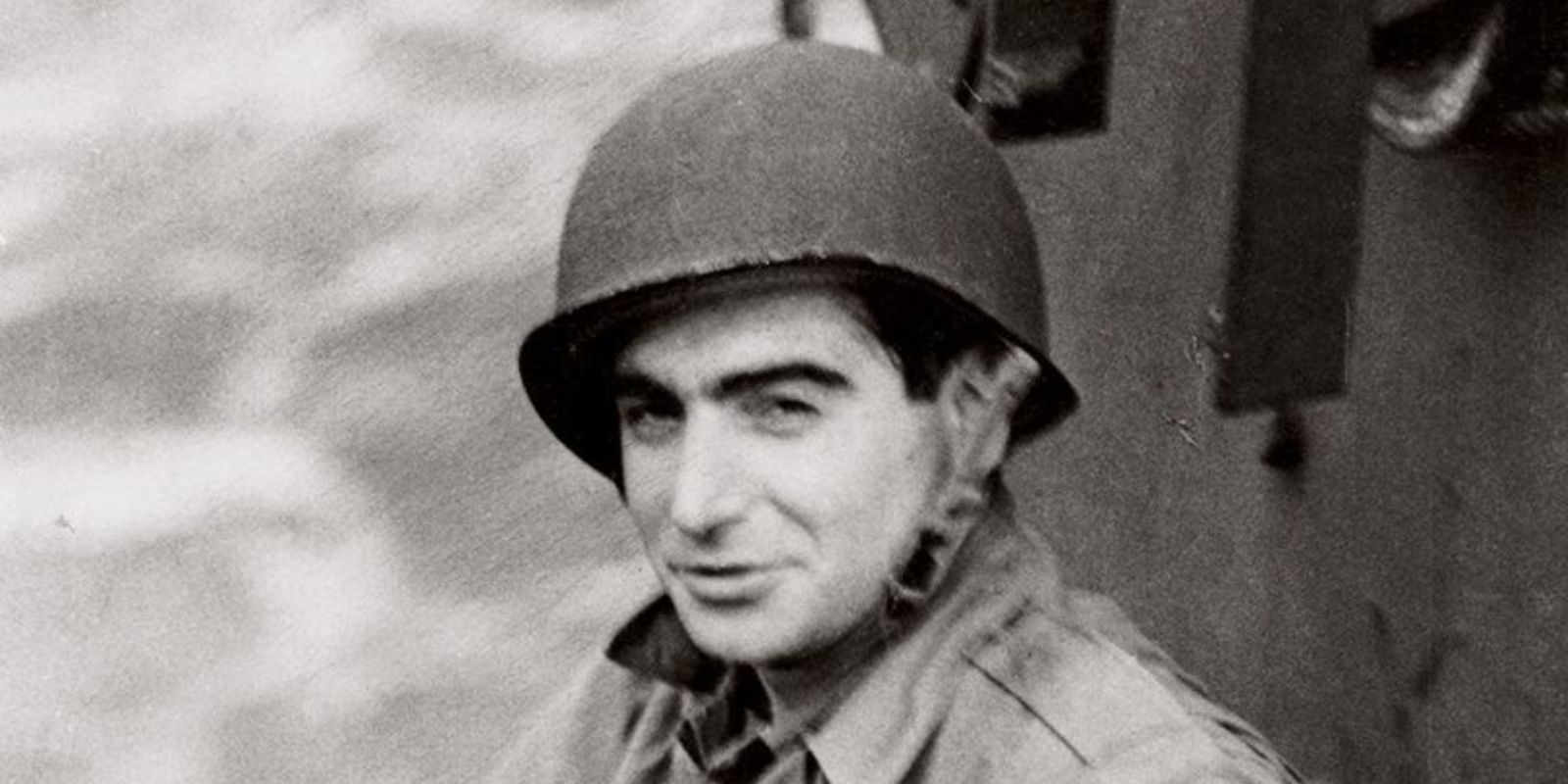 Robert Capa vestindo uniforme militar e capacete, pronto para cobrir mais um conflito. Sua filosofia era clara: "Se suas fotos não são boas o suficiente, você não está perto o suficiente." Essa disposição para se aproximar da ação, arriscando a própria vida, redefiniu o papel do fotógrafo de guerra e resultou em algumas das imagens mais impactantes do século XX. Fonte: Vanity Fair / Condé Nast.