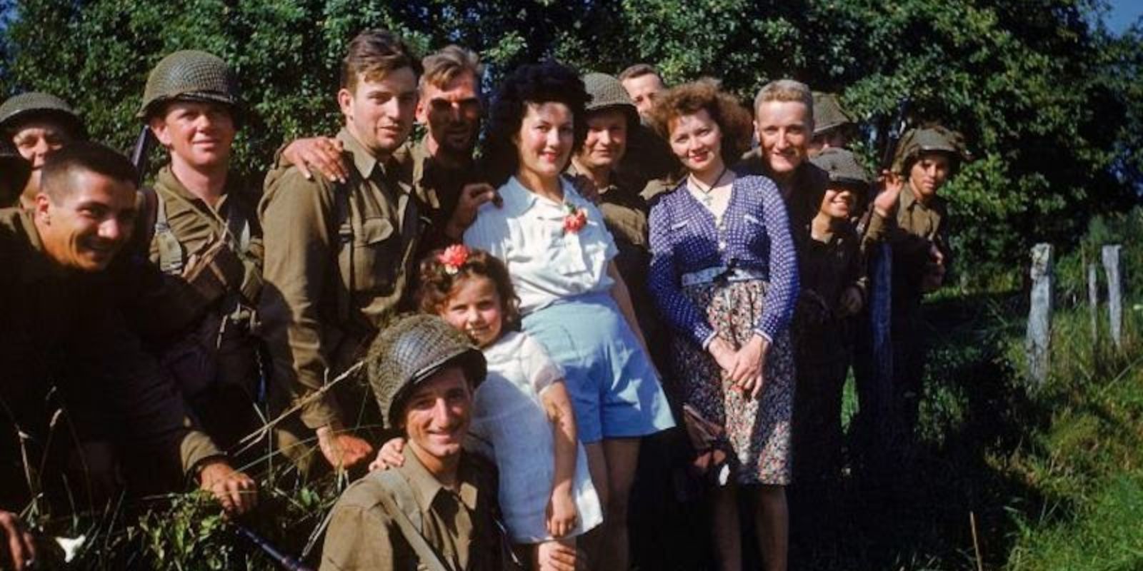 Soldados aliados e civis franceses, incluindo uma criança, posam juntos para uma fotografia. A imagem reflete a atmosfera de alívio e celebração, simbolizando a recepção calorosa dada às tropas libertadoras pela população local. Autor: Frank Scherschel / LIFE Picture Collection.