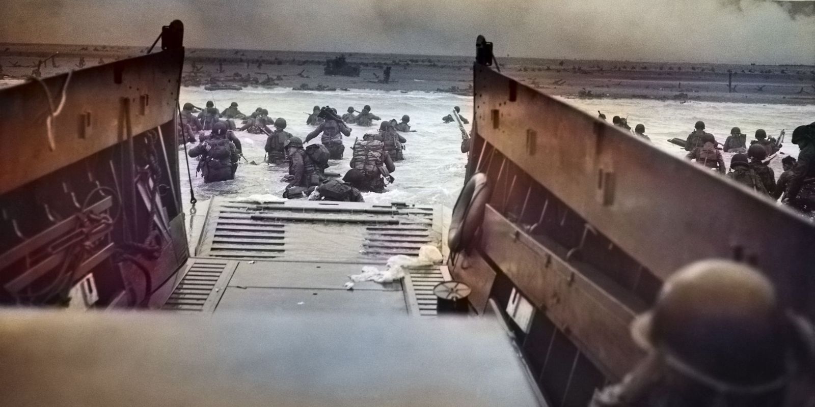 A famosa fotografia "Into the Jaws of Death", colorizada, mostra a visão de dentro de uma embarcação de desembarque (LCVP) da Guarda Costeira dos EUA ao se aproximar da Praia de Omaha. A imagem transmite a ansiedade e a iminência do perigo enfrentado pelos soldados. Fonte: Robert F. Sargent / U.S. Coast Guard.